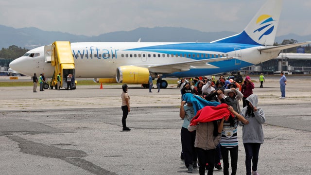 Guatemalan migrants cover their faces upon their arrival from the United States, in Guatemala City 