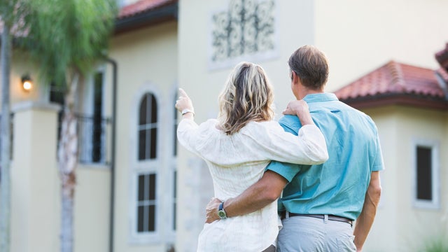 Mature couple standing in front of their mansion 