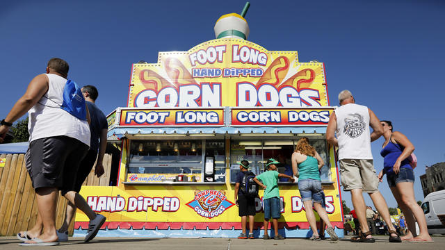 Fairgoers line up to get a corn dog at a concession stand during the opening day of the Iowa State Fair in Des Moines, Iowa, Aug. 9, 2018. 