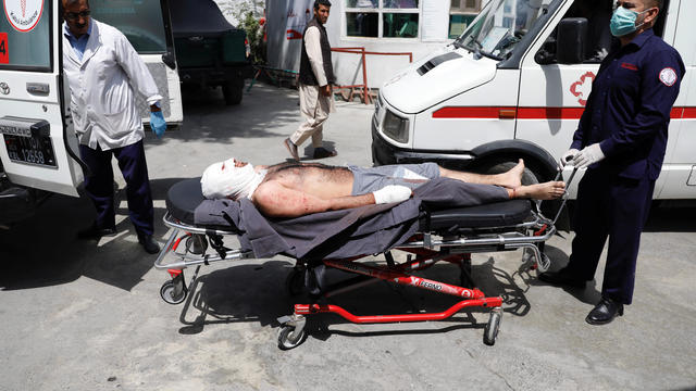 Men carry an injured man to a hospital after a blast in Kabul 