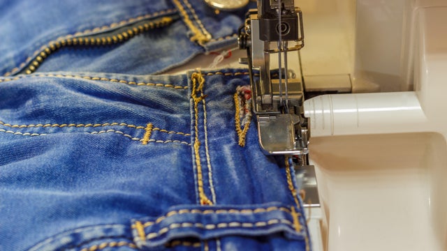 Sewing machine repair jeans trousers, close-up. 
