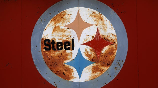 A rusty U.S. Steel "Steelmark" logo rests on the side of a steel business in Peoria 