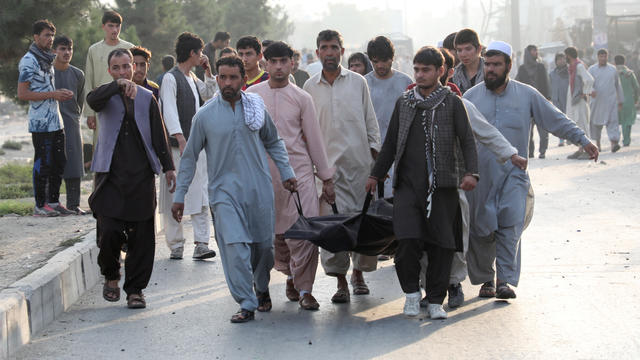 Afghan men carry the dead body of a civilian at the site of a blast in Kabul 