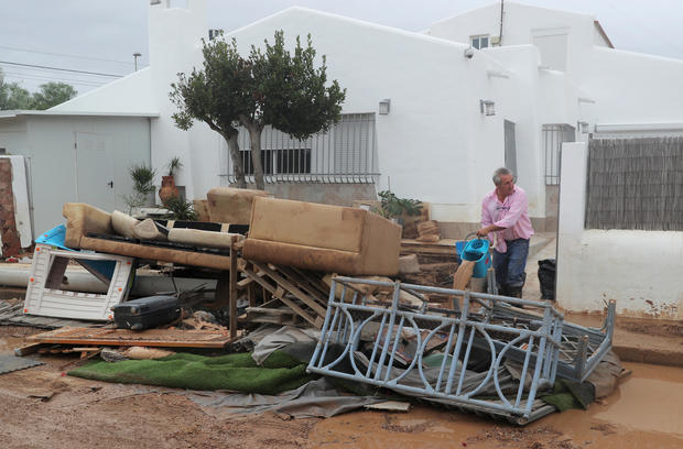 A man cleans an entrance to a house next to damaged furniture after flooding caused by torrential rains in San Javier 