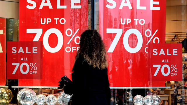 FILE PHOTO: A woman passes sale signs in a shop window in downtown Hamburg 