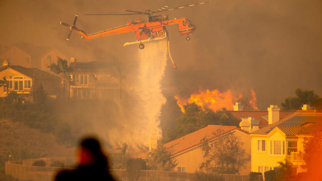 A helicopter drops water to help fight the Saddleridge Fire in the Porter Ranch section of Los Angeles, California, on October 11, 2019. 