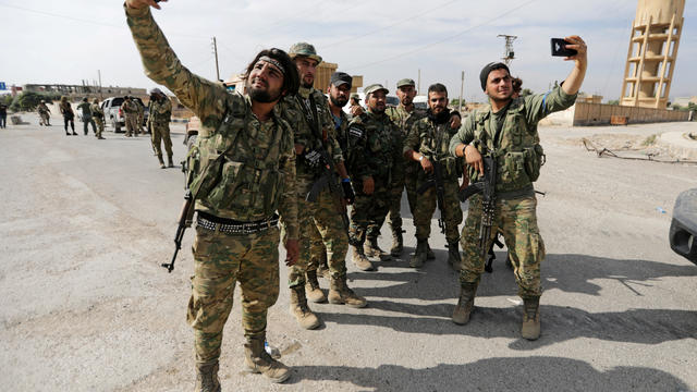 FILE PHOTO: Turkey-backed Syrian rebel fighters take pictures with mobile phones at the border town of Tel Abyad 