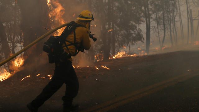 A firefighter pulls a hose along Chalk Hill Road as he battles the wind-driven Kincade Fire in Windsor, California, October 27, 2019. 