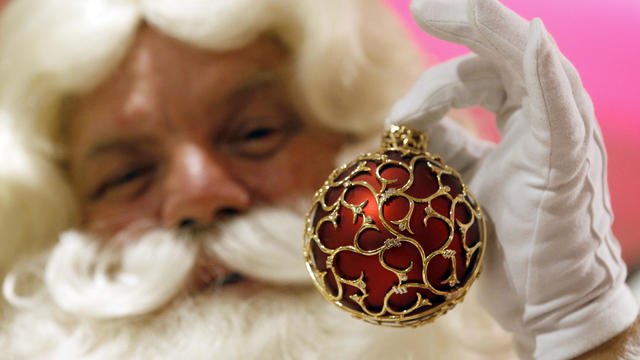 An actor dressed as Father Christmas displays a Christmas bauble to mark the annual opening of Harrods Christmas-themed shop, at Harrods department store in London 