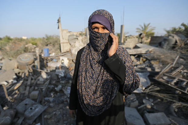 Palestinian woman looks on as she stands in front of a house destroyed in an Israeli air strike in the southern Gaza Strip 