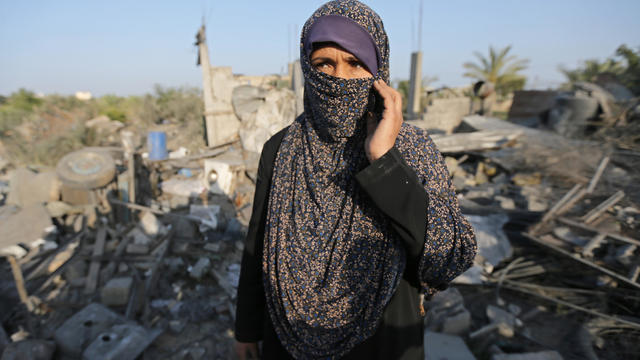 Palestinian woman looks on as she stands in front of a house destroyed in an Israeli air strike in the southern Gaza Strip 