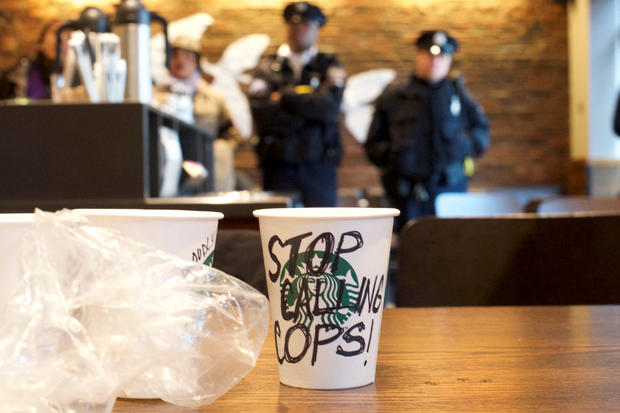 A Starbucks coffee cup with "Stop Calling Cops!" written on the side sits on a table as police monitor protestors demonstrating inside a Center City Starbucks, where two black men were arrested, in Philadelphia 