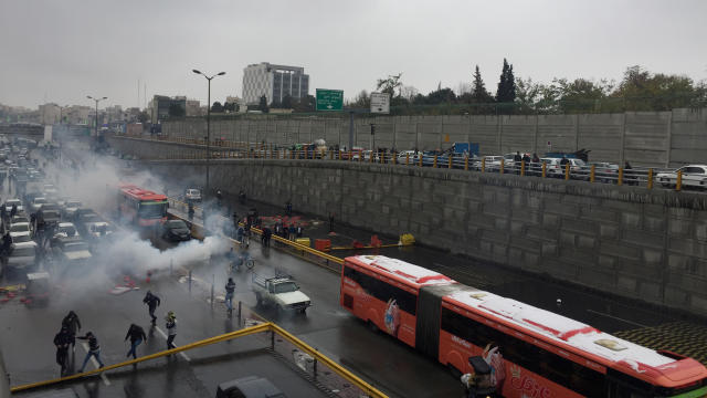 Riot police tries to disperse people as they protest on a highway against increased gas price in Tehran 