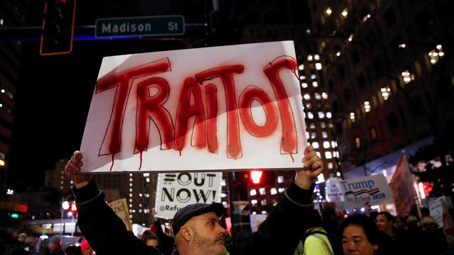 A man holds a sign reading "traitor" as protesters take part in a rally to support the impeachment and removal of President Trump in Seattle 