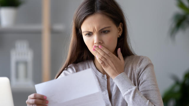 Shocked stressed young woman reading document letter about debt 