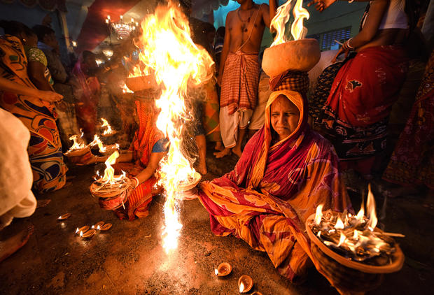 Hindu women are seen seated with burning fire pots on their 