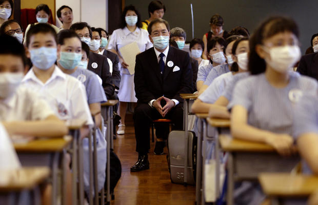 Secretary for Education and Manpower Arthur Li Kwok-cheung attends a lesson in a class in Baptist Lui Ming Choi Primary School in Shatin on the first day of returning to school since the SARS outbreak.  12 May 2003 