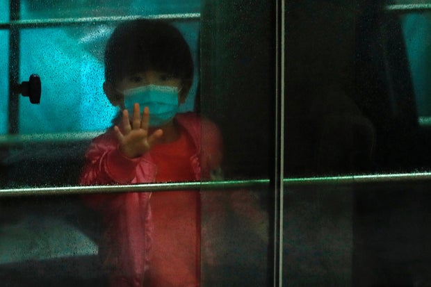 A child waves as she sits in a vehicle carrying residents evacuated from a public housing building, following the outbreak of the novel coronavirus, outside Hong Mei House, at Cheung Hong Estate in Hong Kong