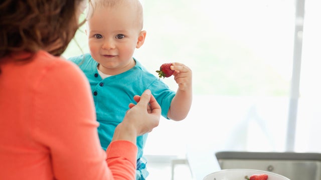 Mother giving baby strawberry 