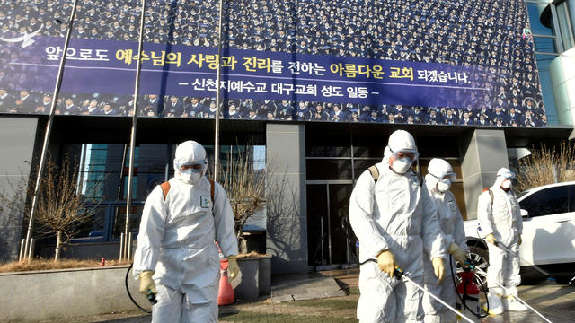 Workers from a disinfection service company sanitize a street in front of a branch of the Shincheonji Church of Jesus the Temple of the Tabernacle of the Testimony where a woman known as "Patient 31" attended a service in Daegu 