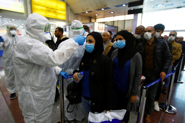 Iraqi medical staff check passengers' temperature upon their arrival at Najaf airport February 20, 2020. 