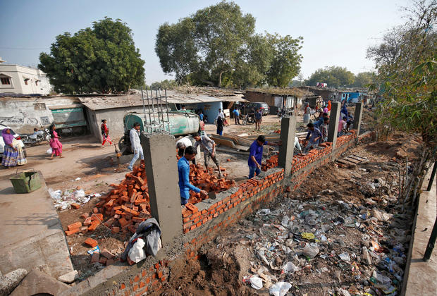 Construction workers build a wall along a slum area as part of a beautification drive along a route that President Trump and India's Prime Minister Narendra Modi will be taking during Mr. Trump's visit to Ahmedabad, India, February 13, 2020. 