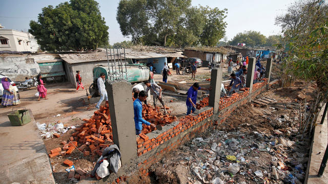 Construction workers build a wall along a slum area as part of a beautification drive along a route that President Trump and India's Prime Minister Narendra Modi will be taking during Mr. Trump's visit to Ahmedabad, India, February 13, 2020. 