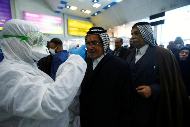 An Iraqi medical staff checks passengers' temperature, amid the new coronavirus outbreak, upon their arrival at Najaf airport 