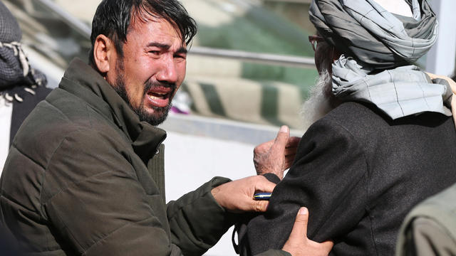 Afghan men cry at a hospital after they heard that their relative was killed during an attack in Kabul 