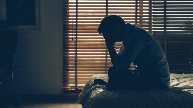 Sad businessman sitting head in hands on the bed in the dark bedroom with low light environment, dramatic concept, vintage tone color 