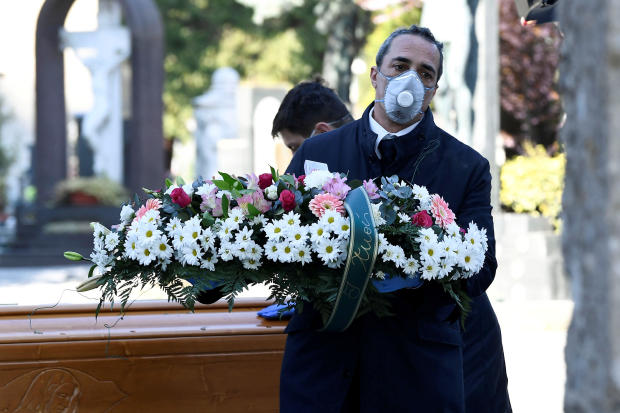 Cemetery workers and funeral agency workers in protective masks transport the coffin of a person who died from the coronavirus disease COVID-19 into a cemetery in Bergamo, Italy, March 16, 2020. 