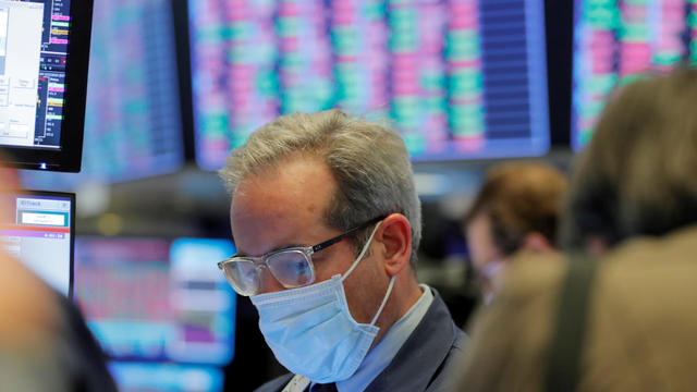 FILE PHOTO: A trader wears a mask as he works on the floor of the New York Stock Exchange (NYSE) as the building prepares to close indefinitely due to the coronavirus disease (COVID-19) outbreak in New York 