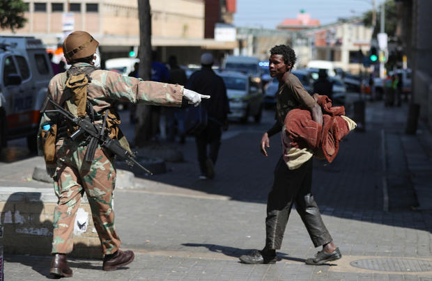 A member of the South African National Defence Forces gestures to a homeless men during their patrols on the first day of a nationwide lockdown in Johannesburg 