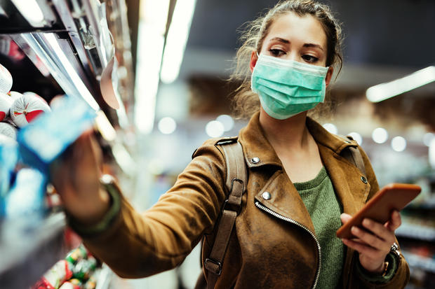 coronavirus Woman wearing protective mask while using cell phone and buying food in grocery store during virus epidemic. 