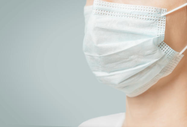 Unrecognizable woman in medical protective mask, close-up. 