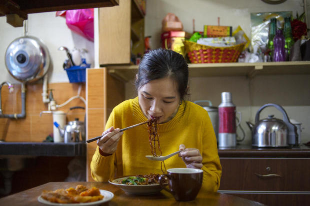 Asian woman eating noddle using chopsticks at home 