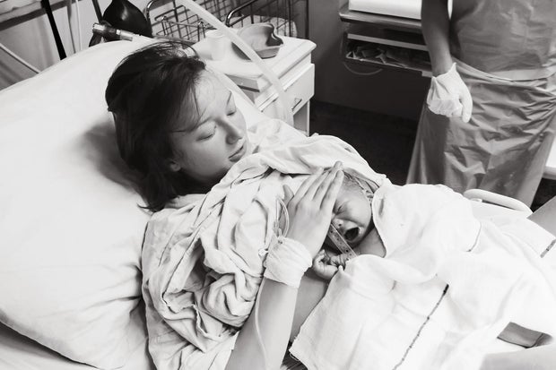 Mother holding her newborn baby child after labor in a hospital.