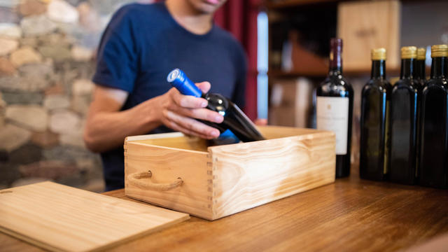 Salesman packing a wine bottle in wooden box 