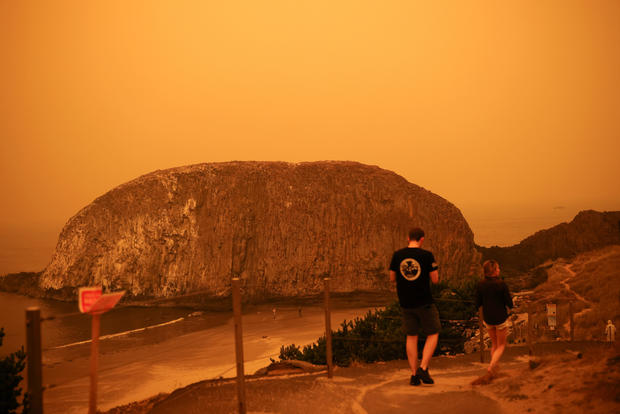 People walk by the Pacific Ocean coast as smoke from wildfires covers an area near Seal Rock, Oregon 