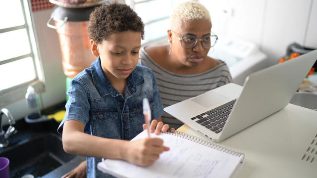 Mother helping her son studying with laptop on a online class at home 