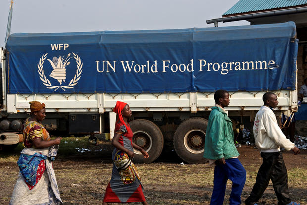 FILE PHOTO: Displaced Congolese civilians walk past a truck carrying food for distribution at Kibati, just outside the eastern Congolese city of Goma 