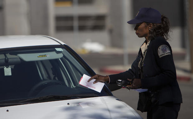 HOLLYWOOD, CA - NOVEMBER 3, 2014: A parking enforcement officer puts a ticket on a car parked in a n 