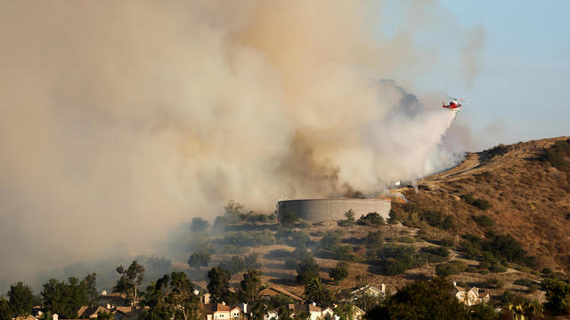 A helicopter drops water over flames from the Silverado Fire near Lake Forest, California, on October 27, 2020. 