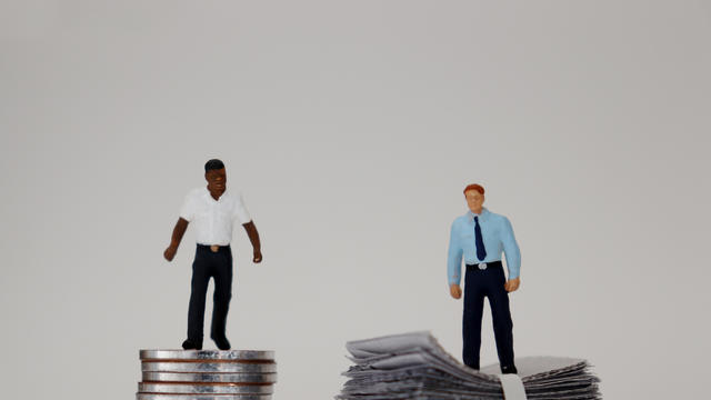 The concept of economic racial discrimination. Money and two miniature men. 