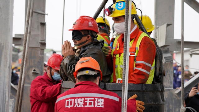 Rescue workers help a miner at the Hushan gold mine after explosion in Qixia, Shandong 