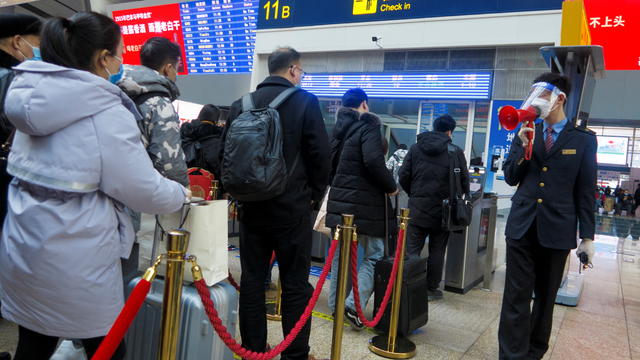 A station staff member speaks through a bullhorn to travellers waiting to board their train at Beijing South Railway station ahead of Lunar New Year celebrations following an outbreak of the coronavirus disease (COVID-19) in Beijing 