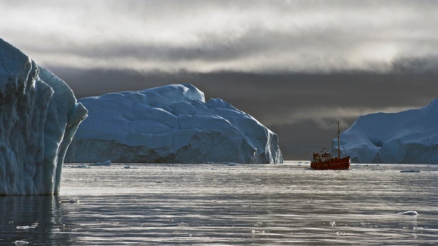 Boat in the water near a Greenland iceberg 