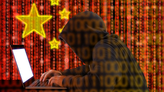 Chinese hacker at work in front of red flag 