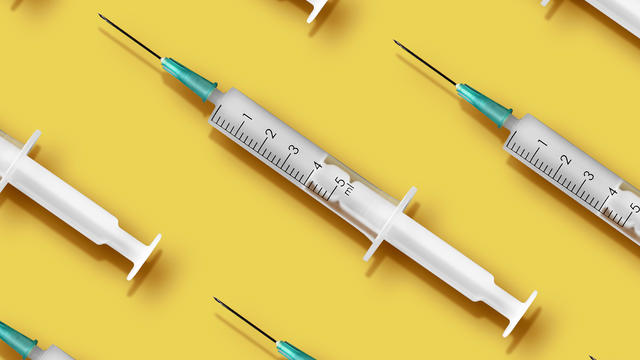 Medical syringes organized in a pattern on yellow background 