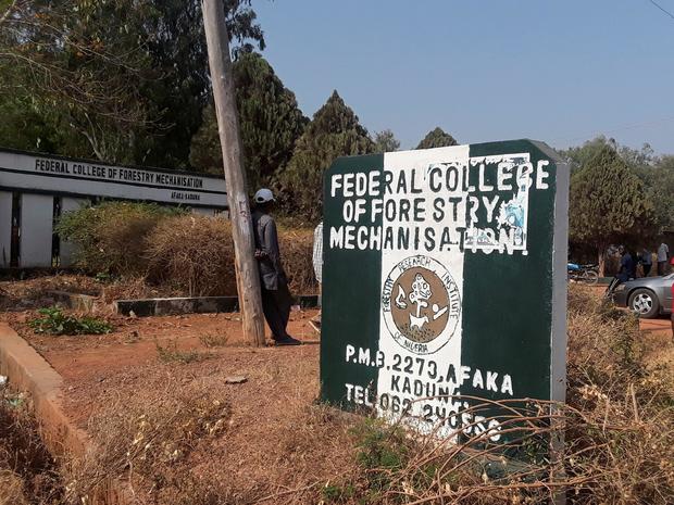 Man rests on a pole beside the signage of the Federal College of Forestry Mechanization where gunmen abducted students, in Kaduna 